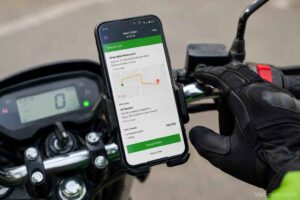Delivery rider checking order on smartphone mounted on motorcycle